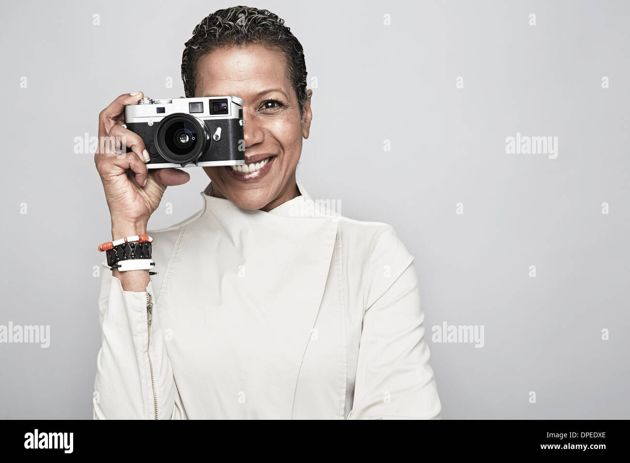 Studio portrait of happy young woman holding up camera Banque D'Images