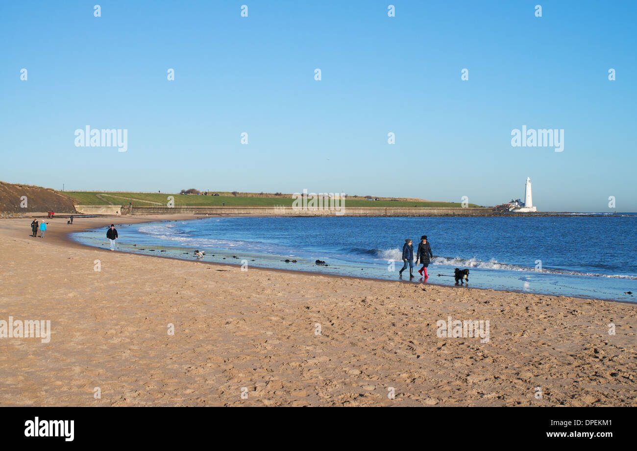 Les chiens les gens qui marchent le long de la plage à Whitley Bay avec St Mary's Island dans l'arrière-plan North East England UK Banque D'Images