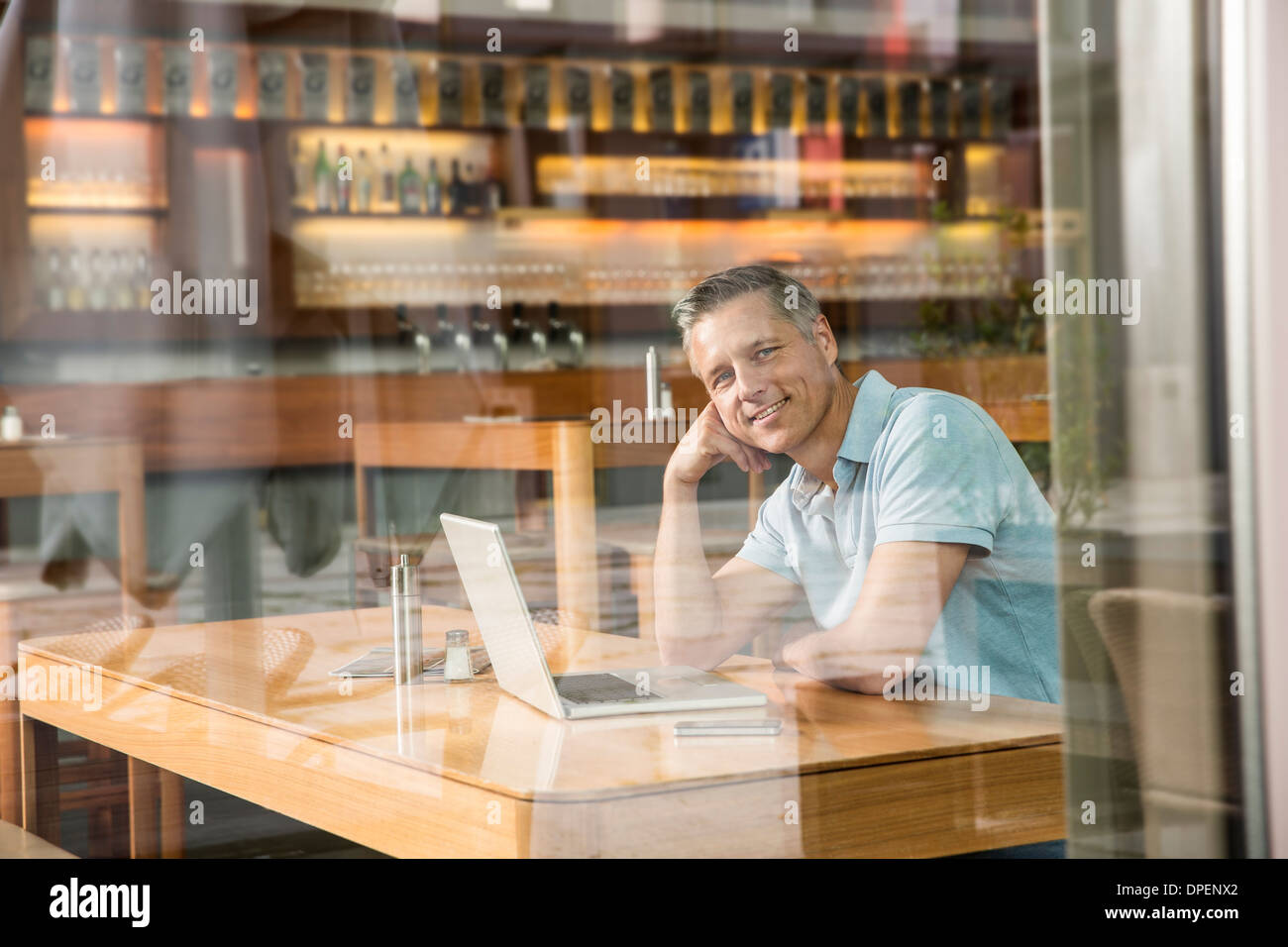 Businessman using laptop, vue à travers la vitre Banque D'Images