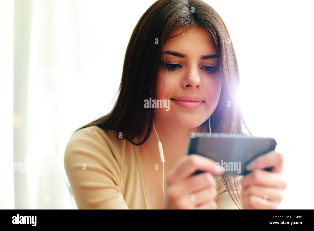 Young happy female student using smartphone à la maison Banque D'Images