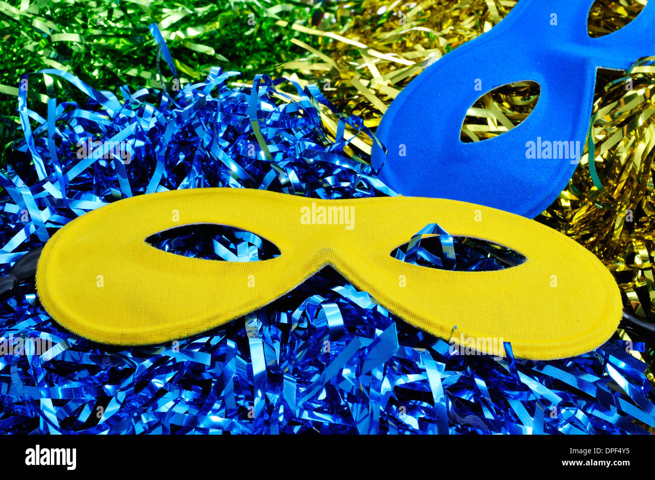 Une paire de masques de carnaval de couleurs différentes sur un arrière-plan avec les guirlandes de couleurs différentes Banque D'Images