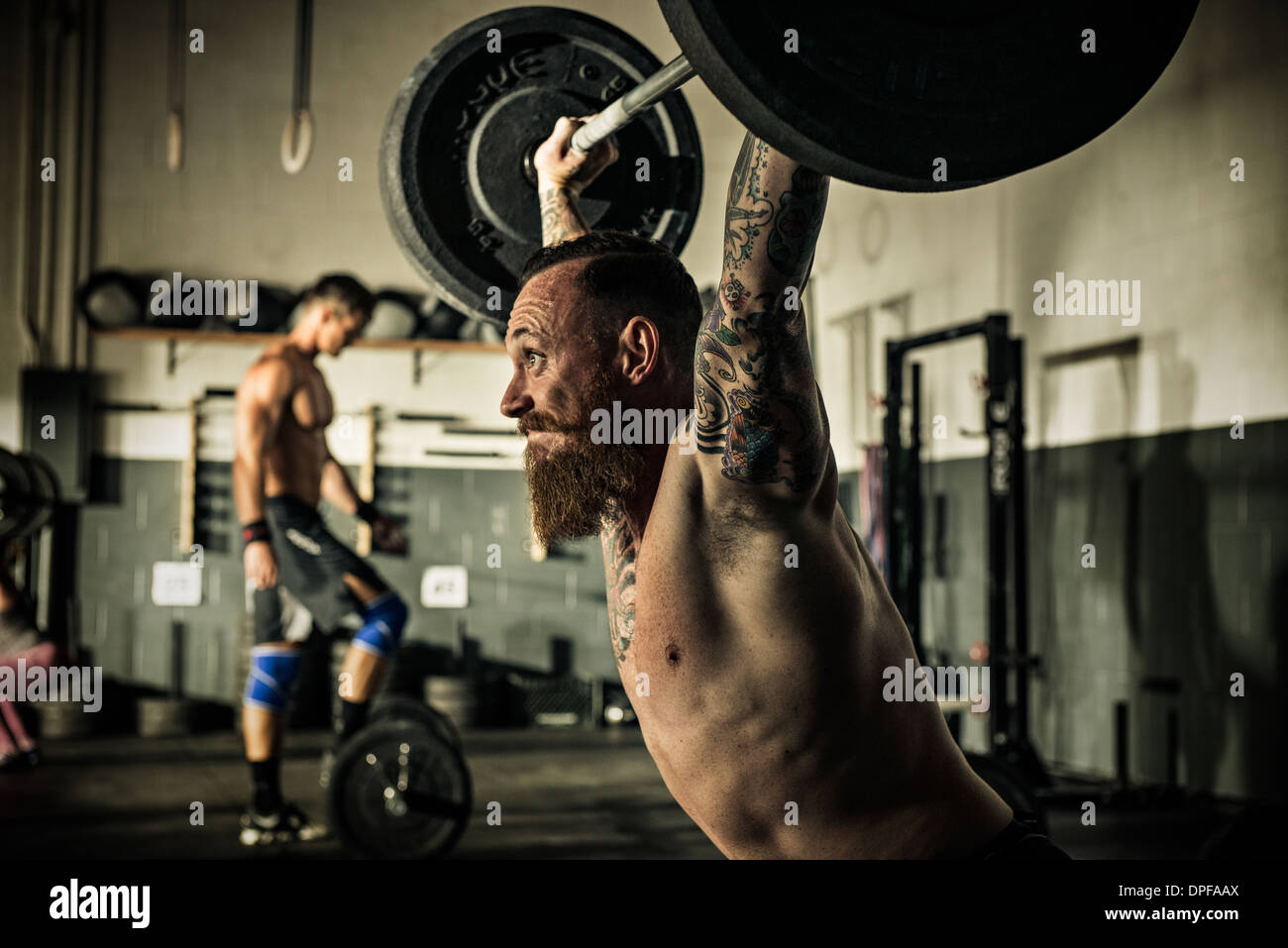 Mid adult man lifting barbell in gymnasium Banque D'Images