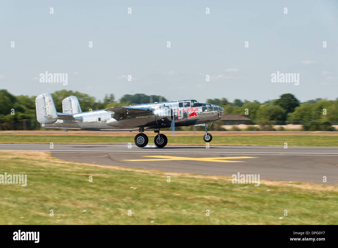 Avec un nuage de fumée des pneus, la silver Red Bull B-25J Mitchell bomber 2 Guerre mondiale touche le sol à l'RIAT 2013 Banque D'Images
