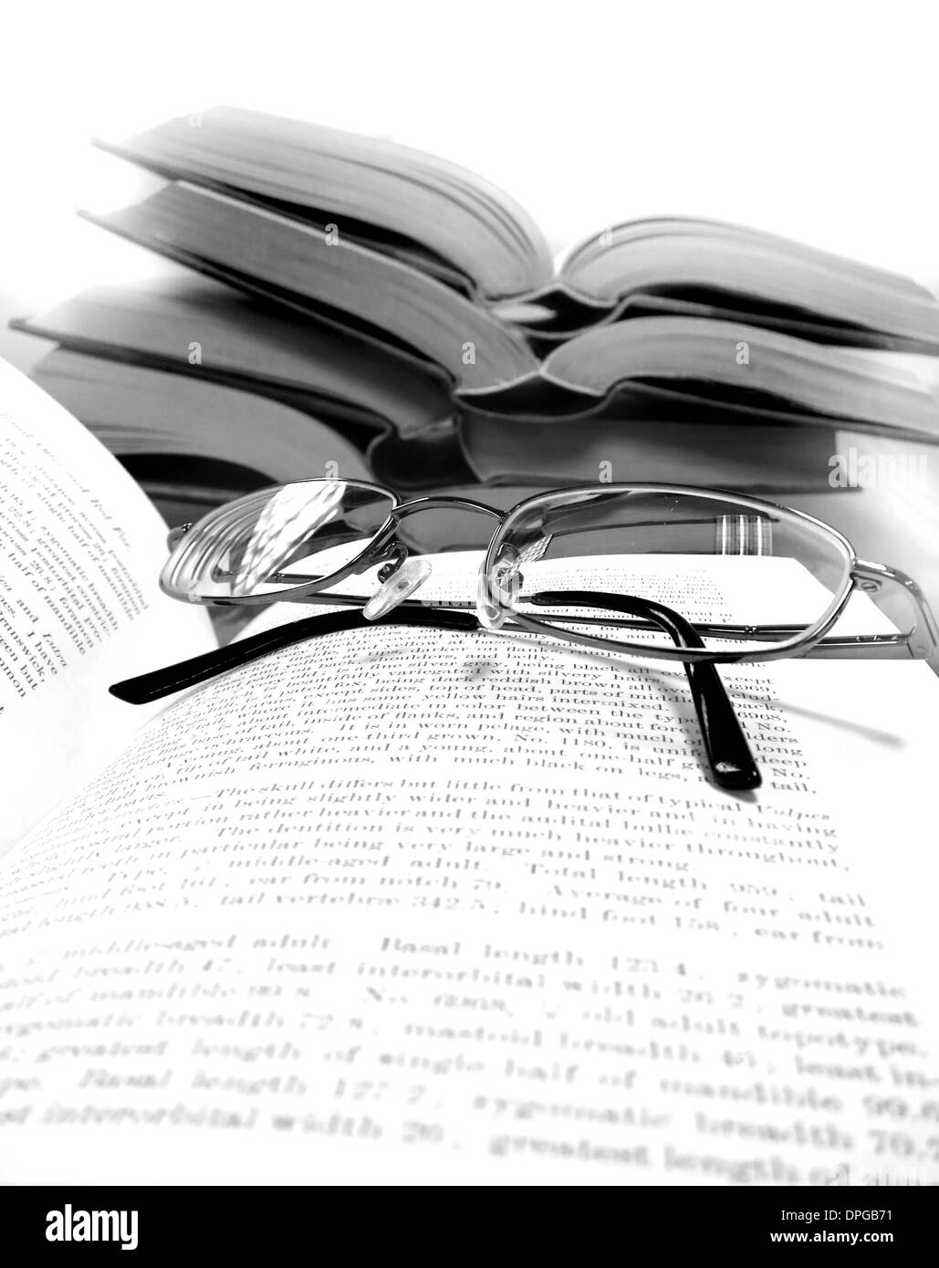Pile de vieux livres sur un bureau ou une table dans une bibliothèque avec des lunettes de lecture Banque D'Images