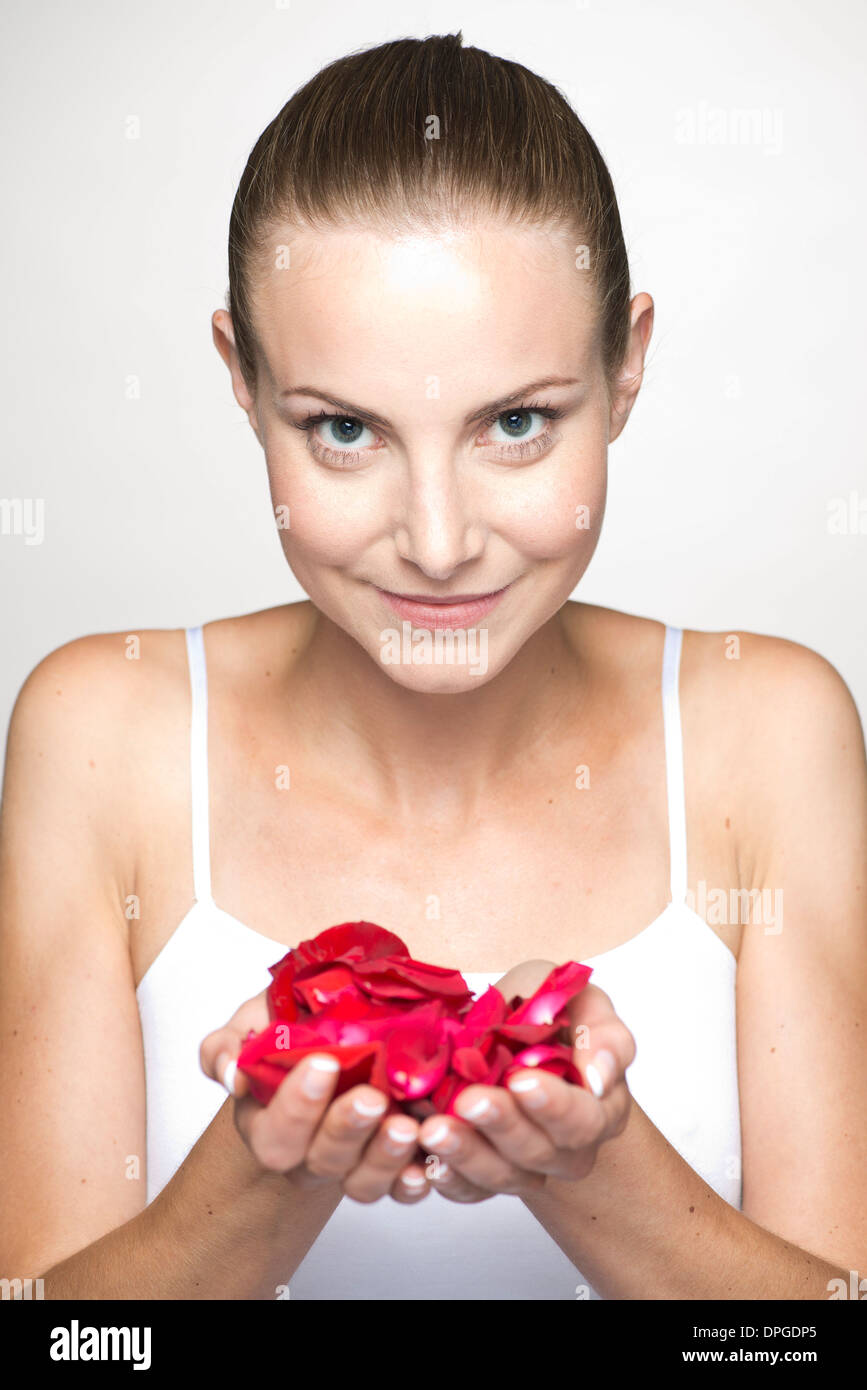 Woman holding rose petals in cupped hands, portrait Banque D'Images