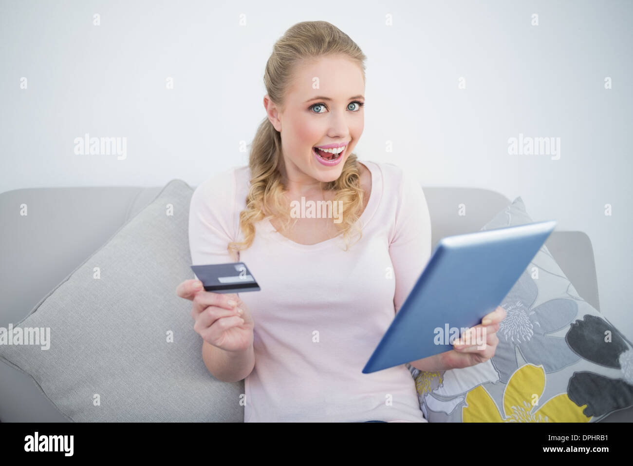 Ravis occasionnels blonde holding tablet et une carte de crédit Banque D'Images