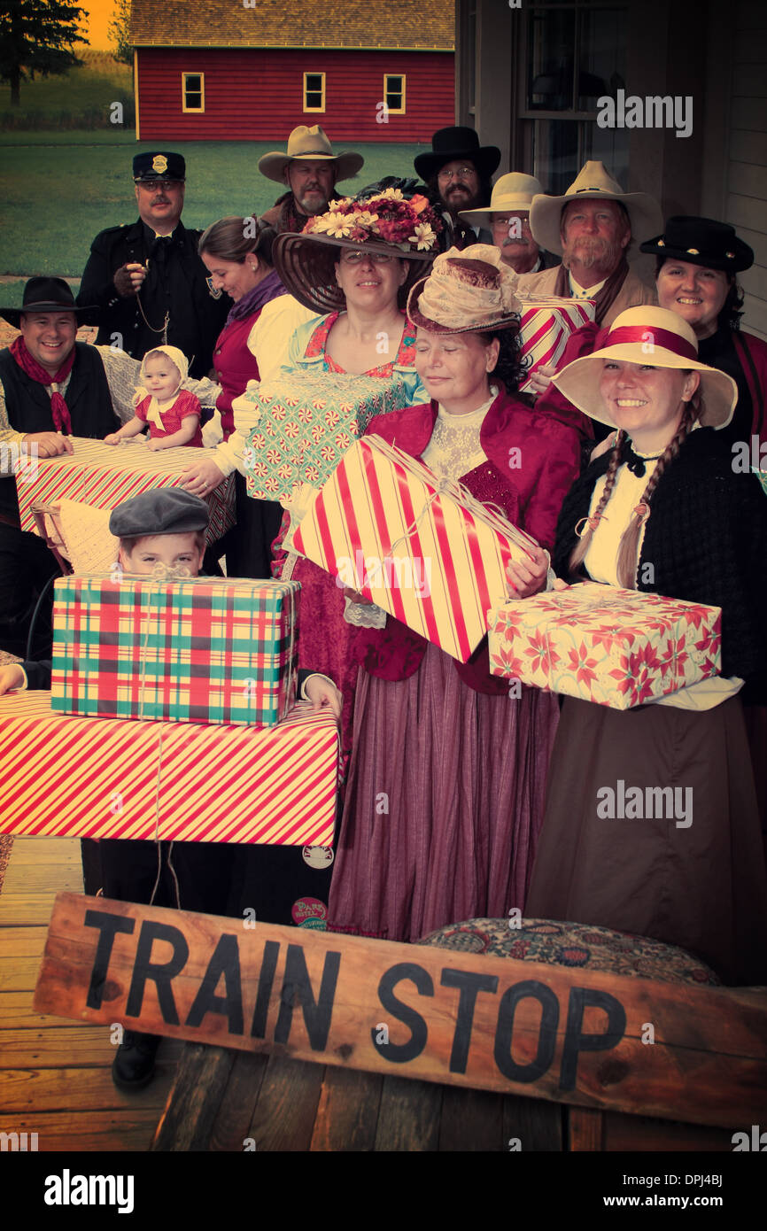Vintage d'un groupe de personnes à l'ancienne en attente à l'arrêt de train avec des cadeaux de Noël Banque D'Images