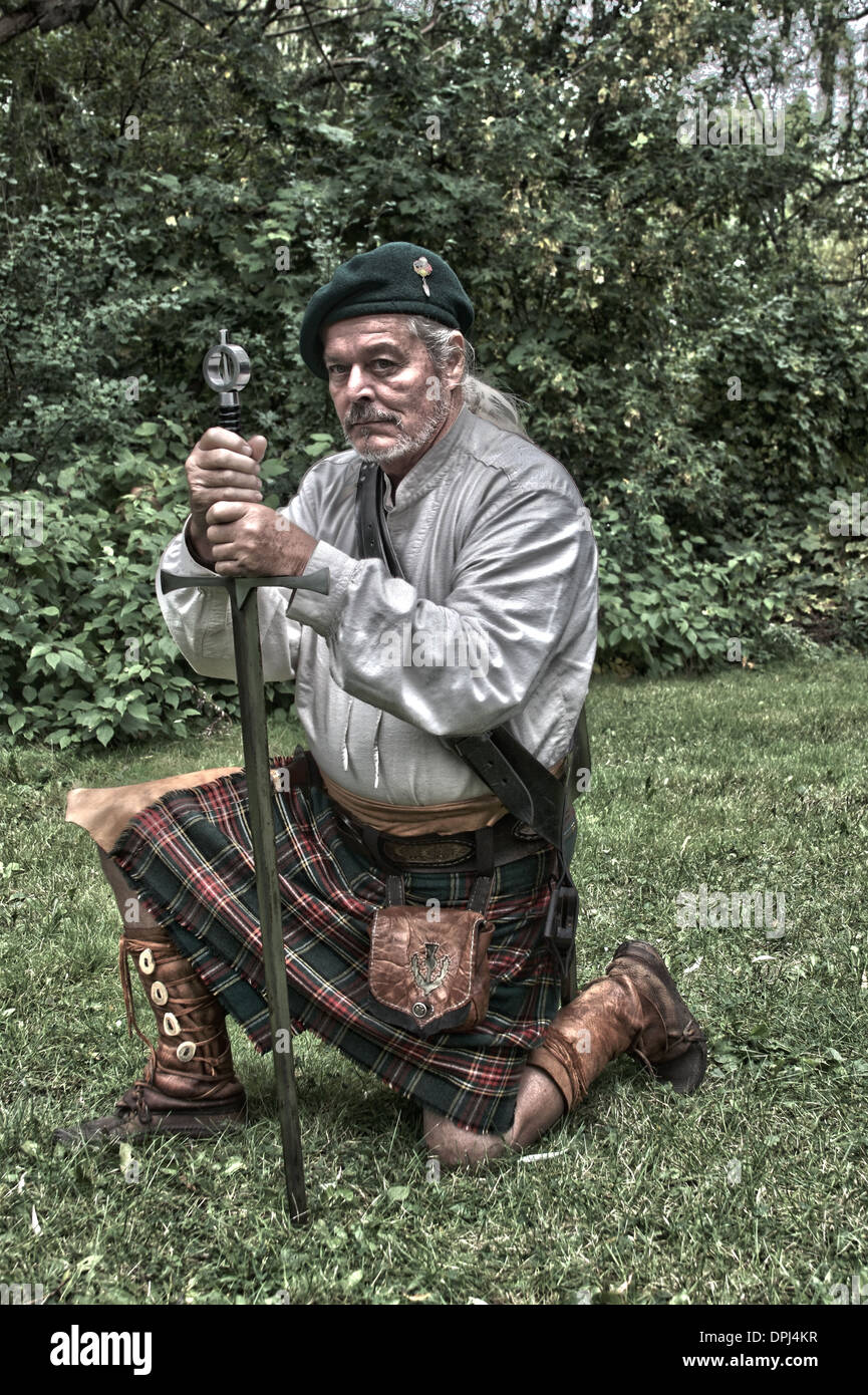 Scottish homme habillé en kilt à genoux avec son épée HDR Banque D'Images