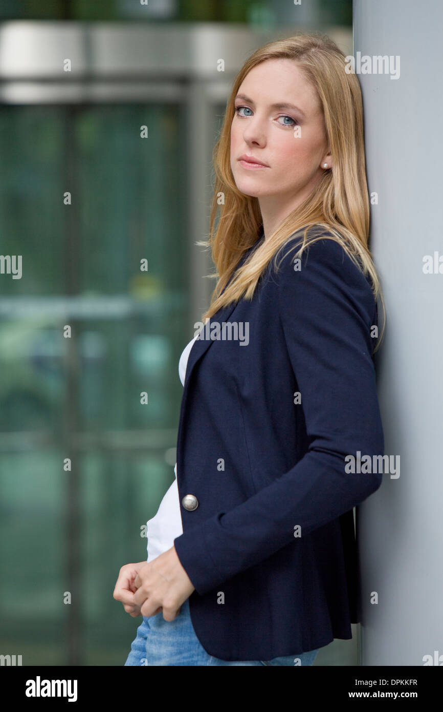 Jeune femme appuyée contre un mur Banque D'Images