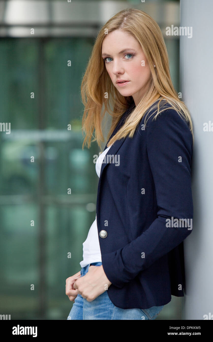 Jeune femme appuyée contre un mur Banque D'Images