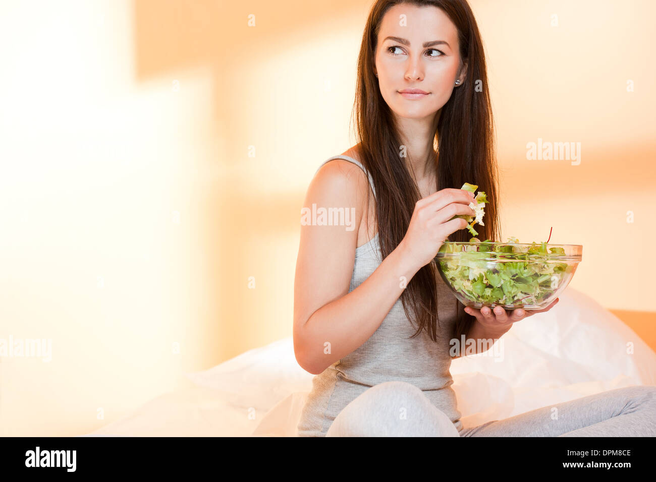 Superbe fit young brunette au lit avec un bol de salade fraîche. Banque D'Images