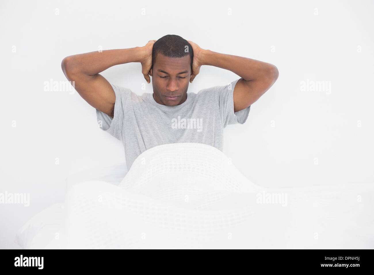 Sleepy Afro homme couvrant les oreilles avec les mains au lit Banque D'Images