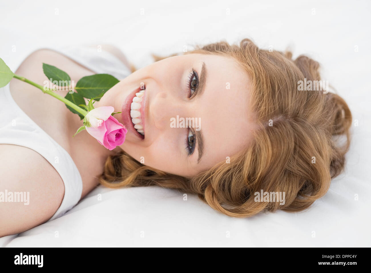 Pretty young woman resting in bed with rose Banque D'Images