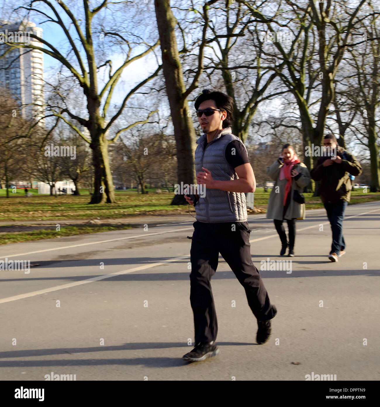 Young man jogging à Hyde Park wearing earphones Banque D'Images