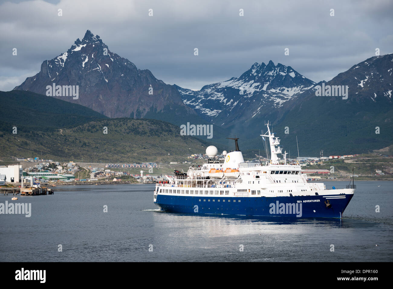 Navire d'expédition Sea Adventurer Monte Olivia Canal de Beagle Ushuaia Argentine | USHUAIA, Argentine — Le navire d'expédition Sea Adventurer, exploité par Quark Expeditions, se prépare à quitter le port d'Ushuaia avec les Andes Fuegiennes s'élevant abruptement en arrière-plan. Le pic triangulaire distinctif du Monte Olivia, atteignant 4 350 pieds (1 326 m), domine l'horizon montagneux au-dessus de la ville. Ushuaia est la principale porte d'entrée mondiale pour les croisières et expéditions en Antarctique, située à environ 621 milles (1 000 km) de la péninsule antarctique à travers le détroit de Drake, et le Sea Adventurer fait partie des navires renforcés pour les glaces Banque D'Images