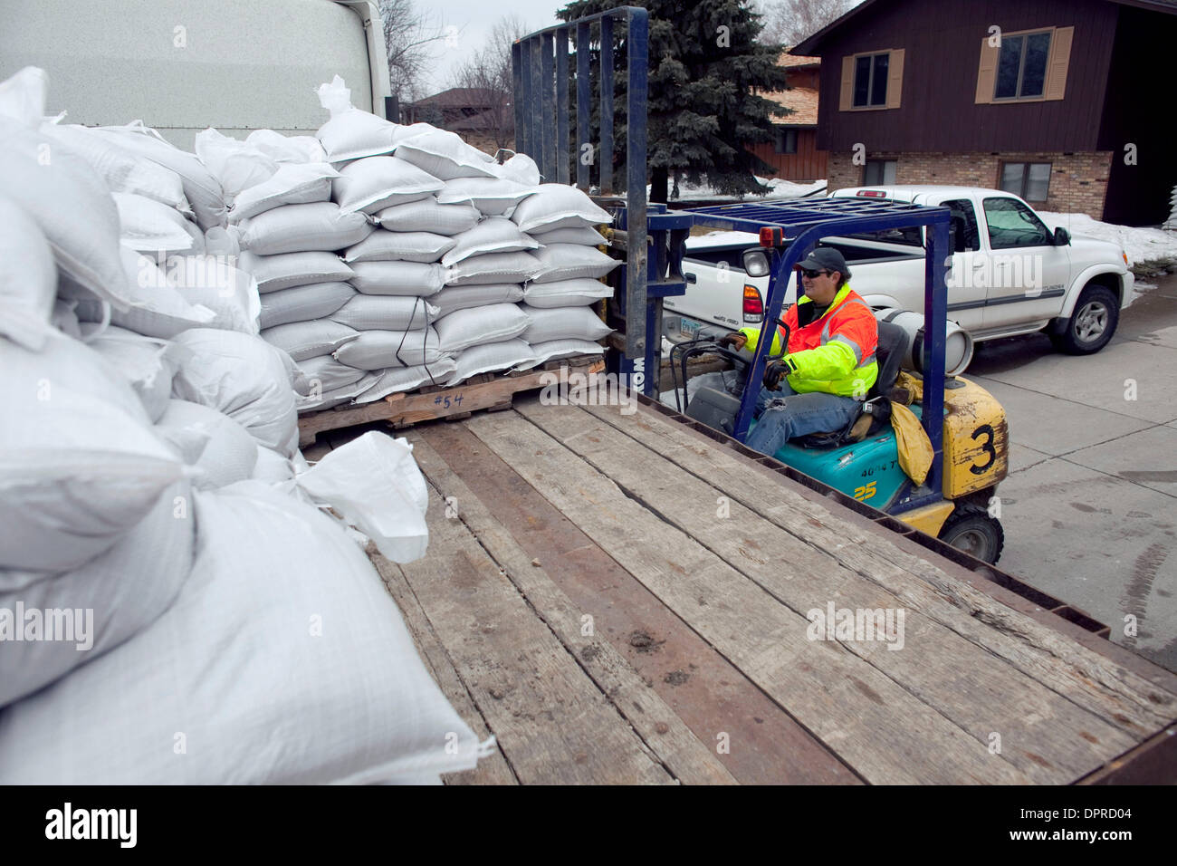 22 mars 2009 - Fargo, Dakota du Nord, USA - DONNIE BECKER palettes déchargement de sacs dans un quartier de Fargo, S. le long de la rivière Rouge. La rivière Rouge le long de la frontière du Minnesota et du Dakota du Nord, est attendu à Crest à ou près des niveaux records dans la semaine à venir. Les résidants des deux côtés de la rivière sont occupés à bâtir des digues et de sacs de sable pour endiguer la montée des eaux. (Crédit image : Banque D'Images