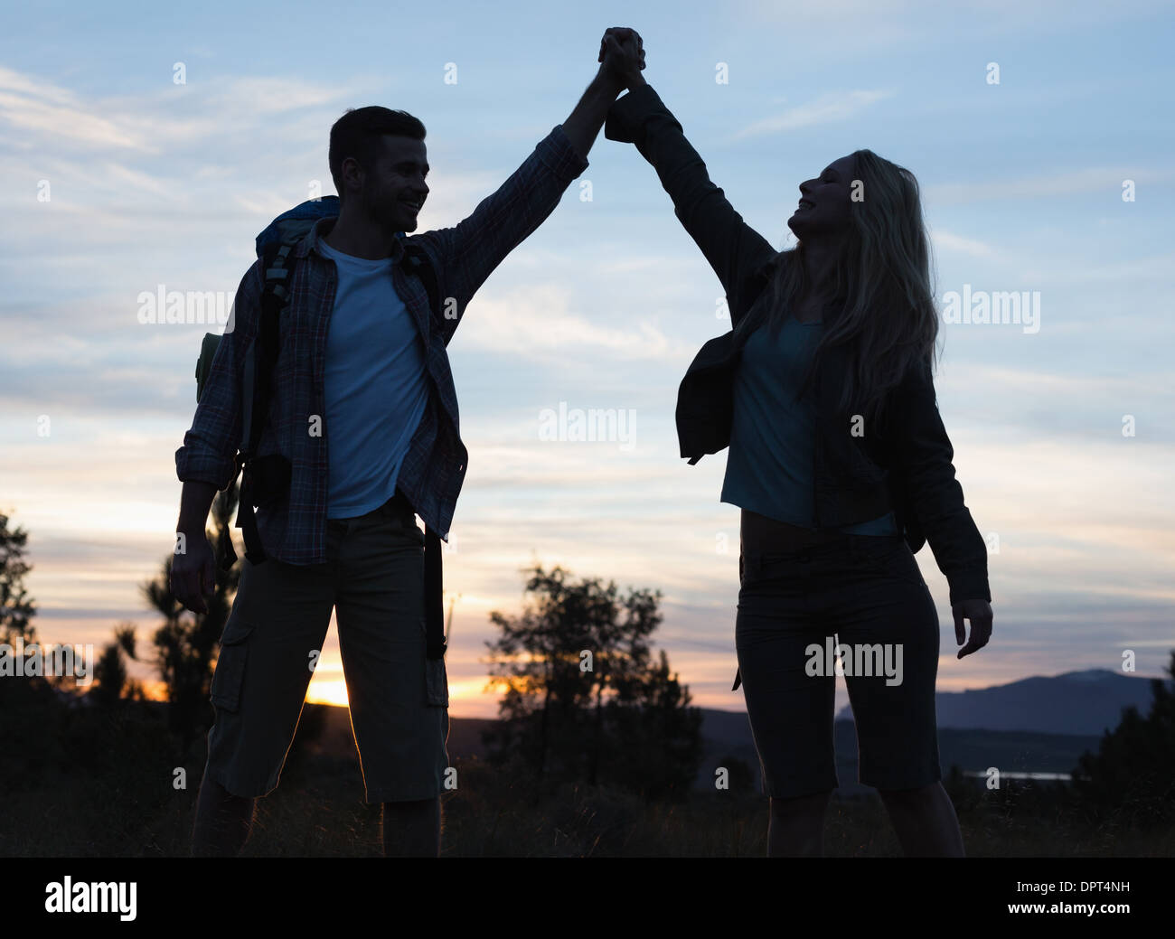 Silhouette couple holding up hands at Dusk Banque D'Images