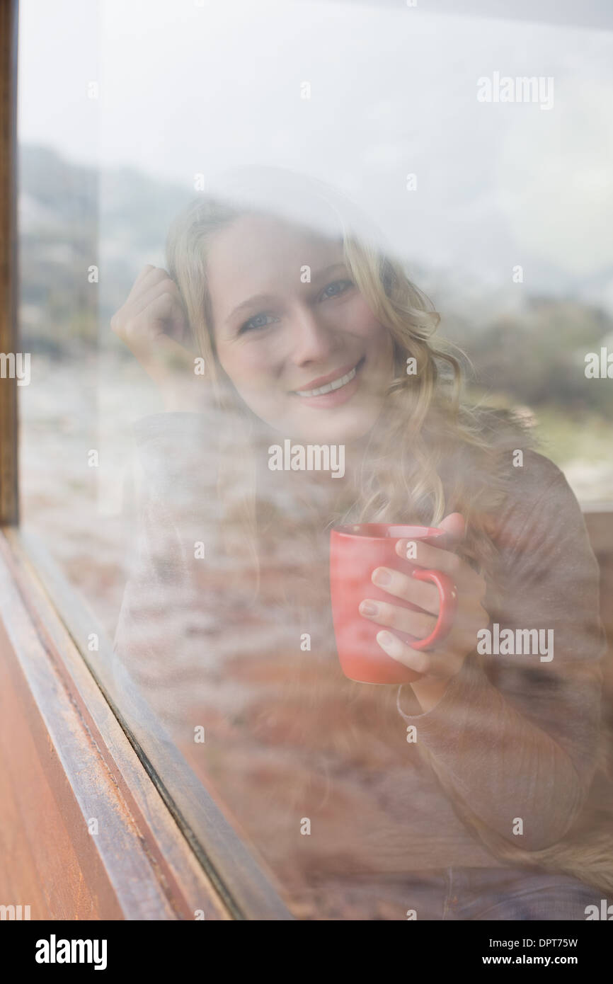 Happy woman with coffee cup à la recherche d'une fenêtre Banque D'Images