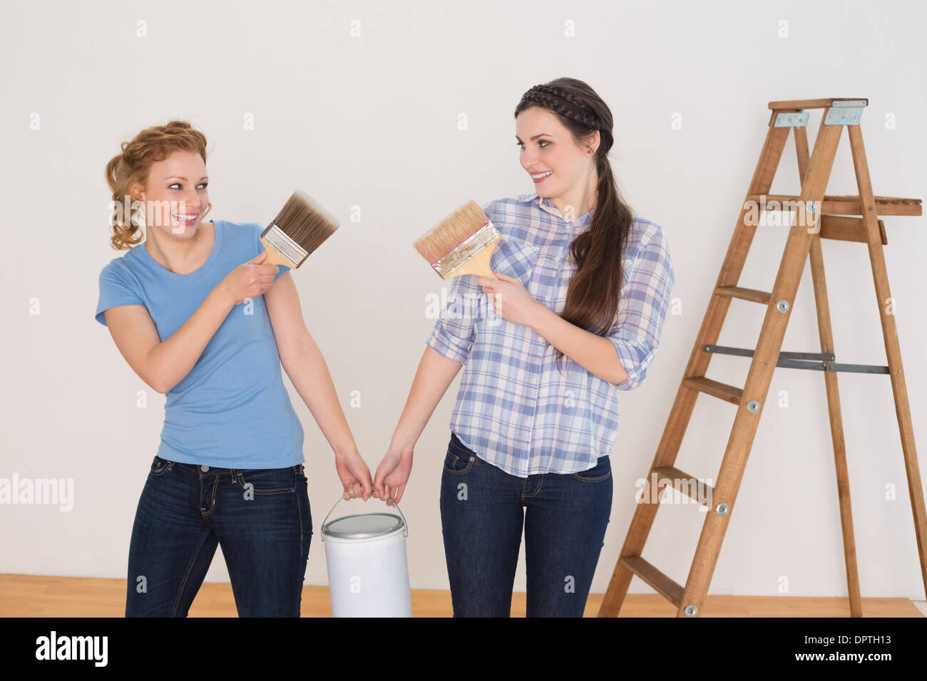 Friends holding peinture pinceaux et peut dans une nouvelle maison Banque D'Images