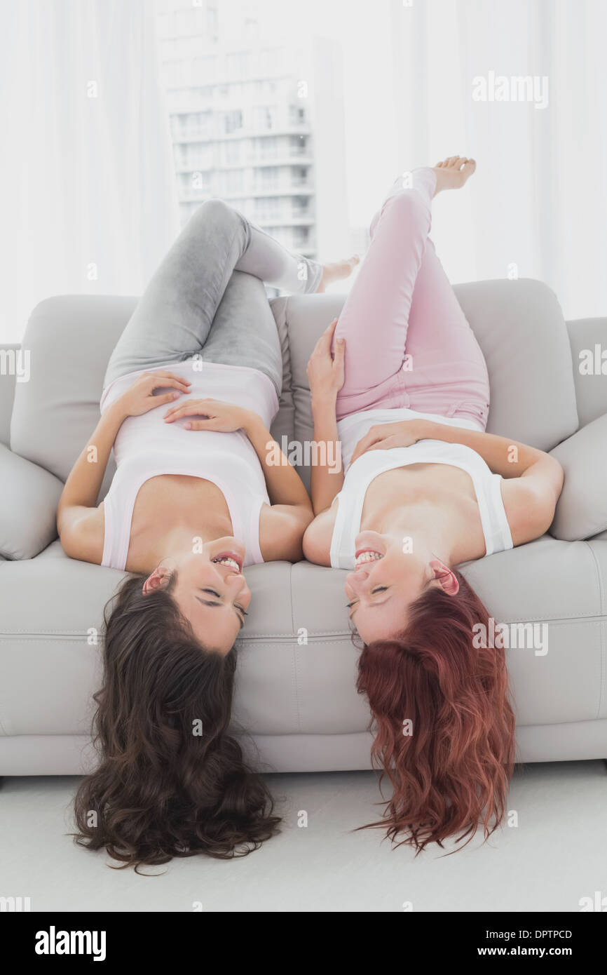 Cheerful brunette et redhead couché à l'envers sur le canapé dans la salle de séjour Banque D'Images