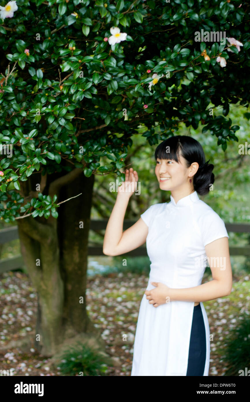 Young woman smiling in woodland park portant une tenue traditionnelle vietnamienne. Banque D'Images