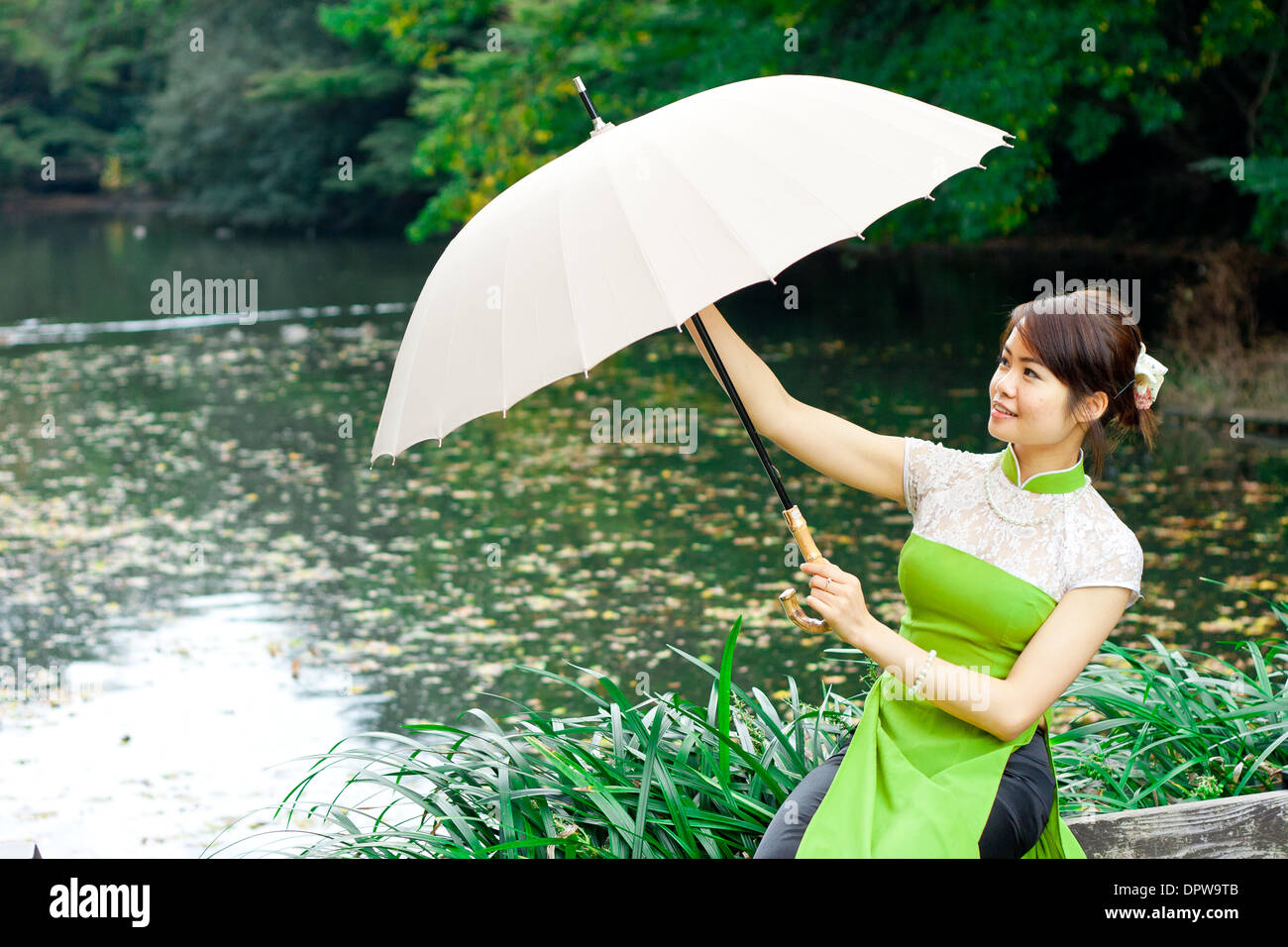 Jeune femme tenant un parapluie à Étang Banque D'Images