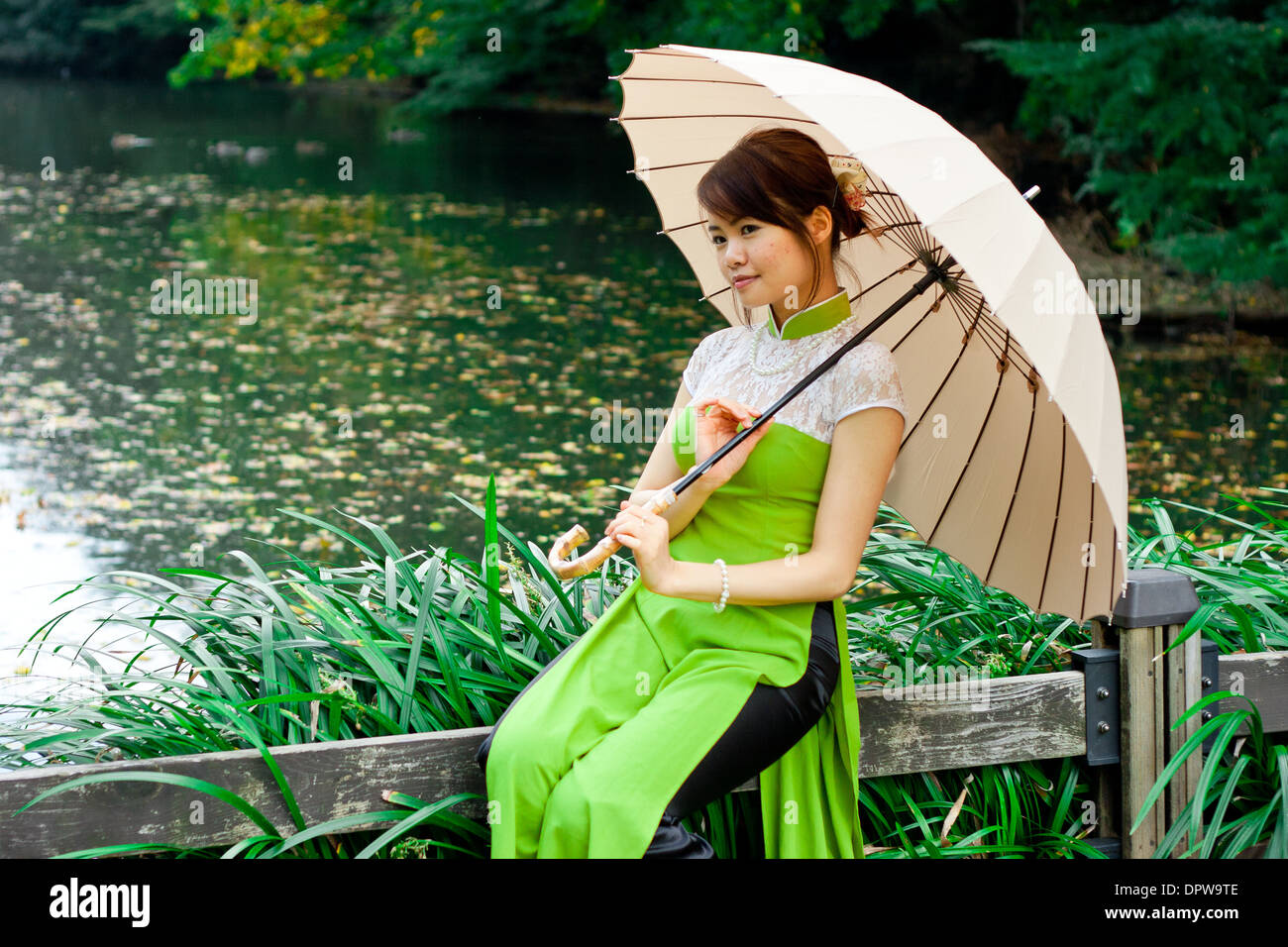 Jeune femme tenant un parapluie à Étang Banque D'Images