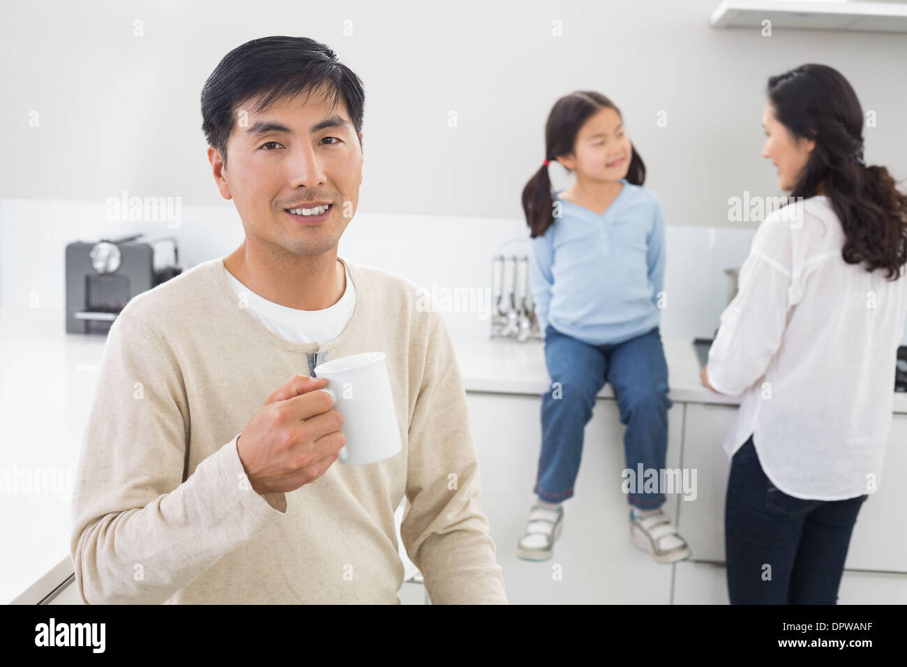 Smiling man holding Coffee cup avec la famille en arrière-plan Banque D'Images