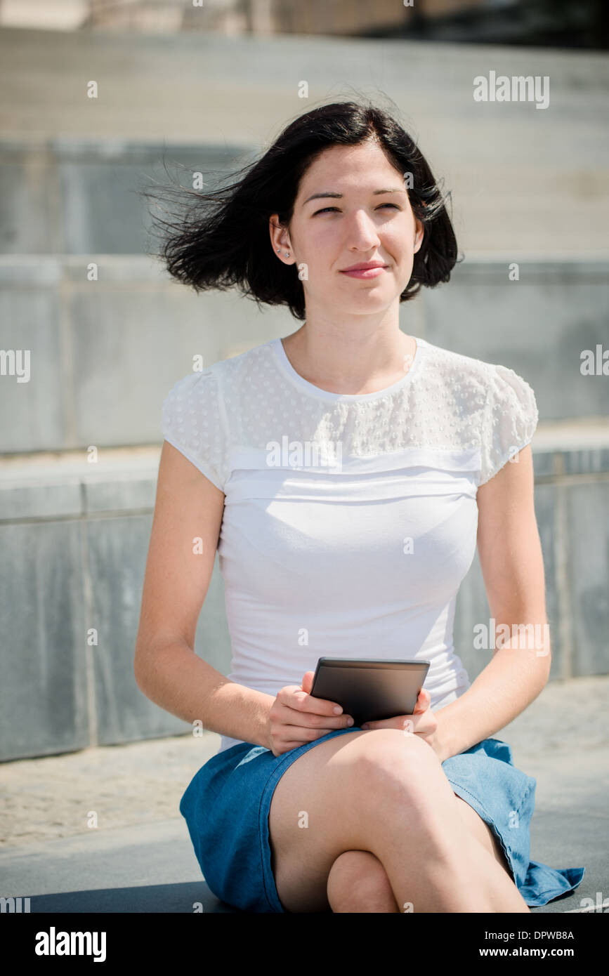 Young woman reading book livre électronique sur l'environnement urbain en-reader Banque D'Images
