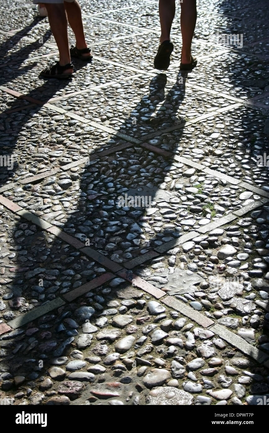 Ombre d'une personne qui marche sur la rue pavée Banque D'Images