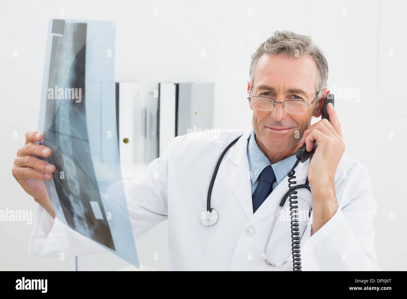 Médecin avec x-ray photo à l'aide de téléphone au bureau Banque D'Images