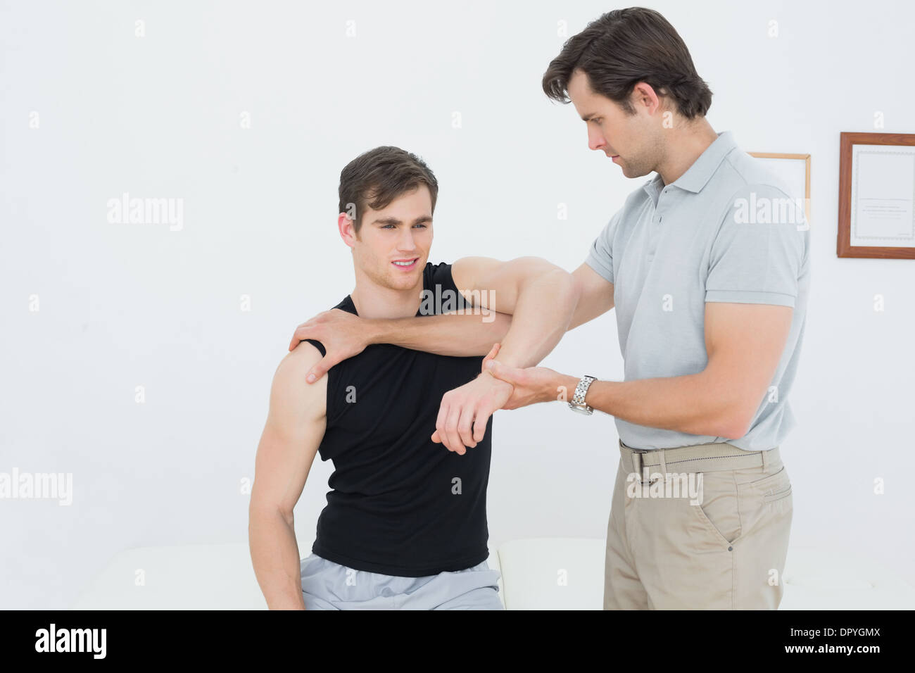 Un jeune mâle physiotherapist examining mans arm Banque D'Images