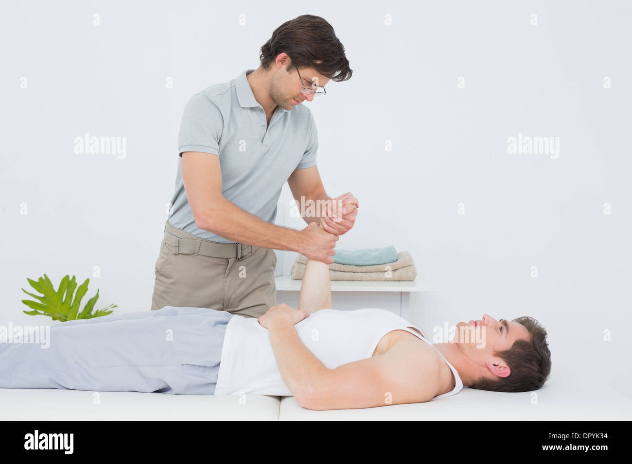 Un jeune mâle physiotherapist examining mans poignet Banque D'Images