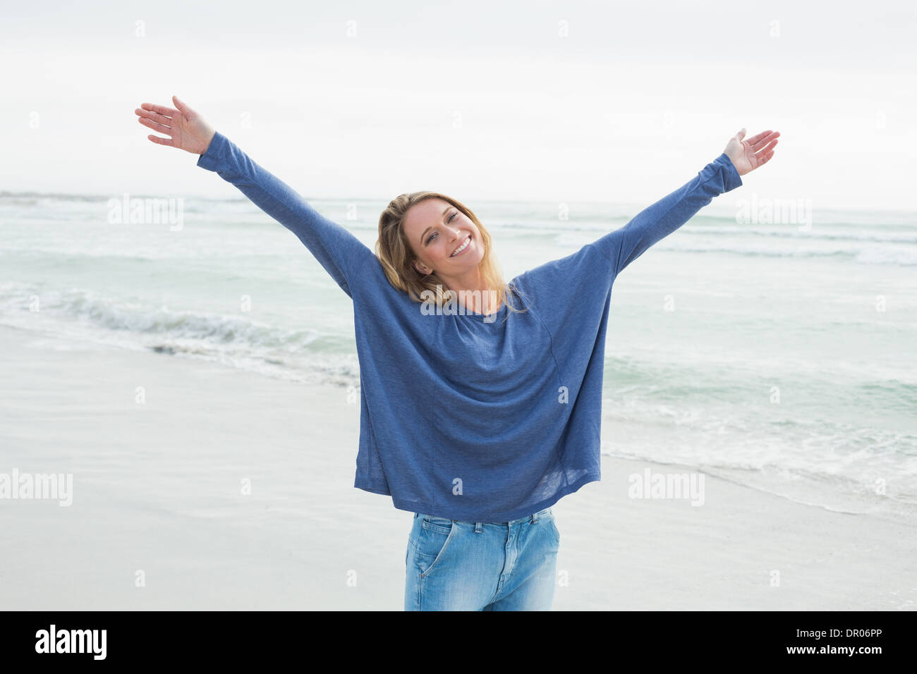 Happy woman with hands raised at beach Banque D'Images