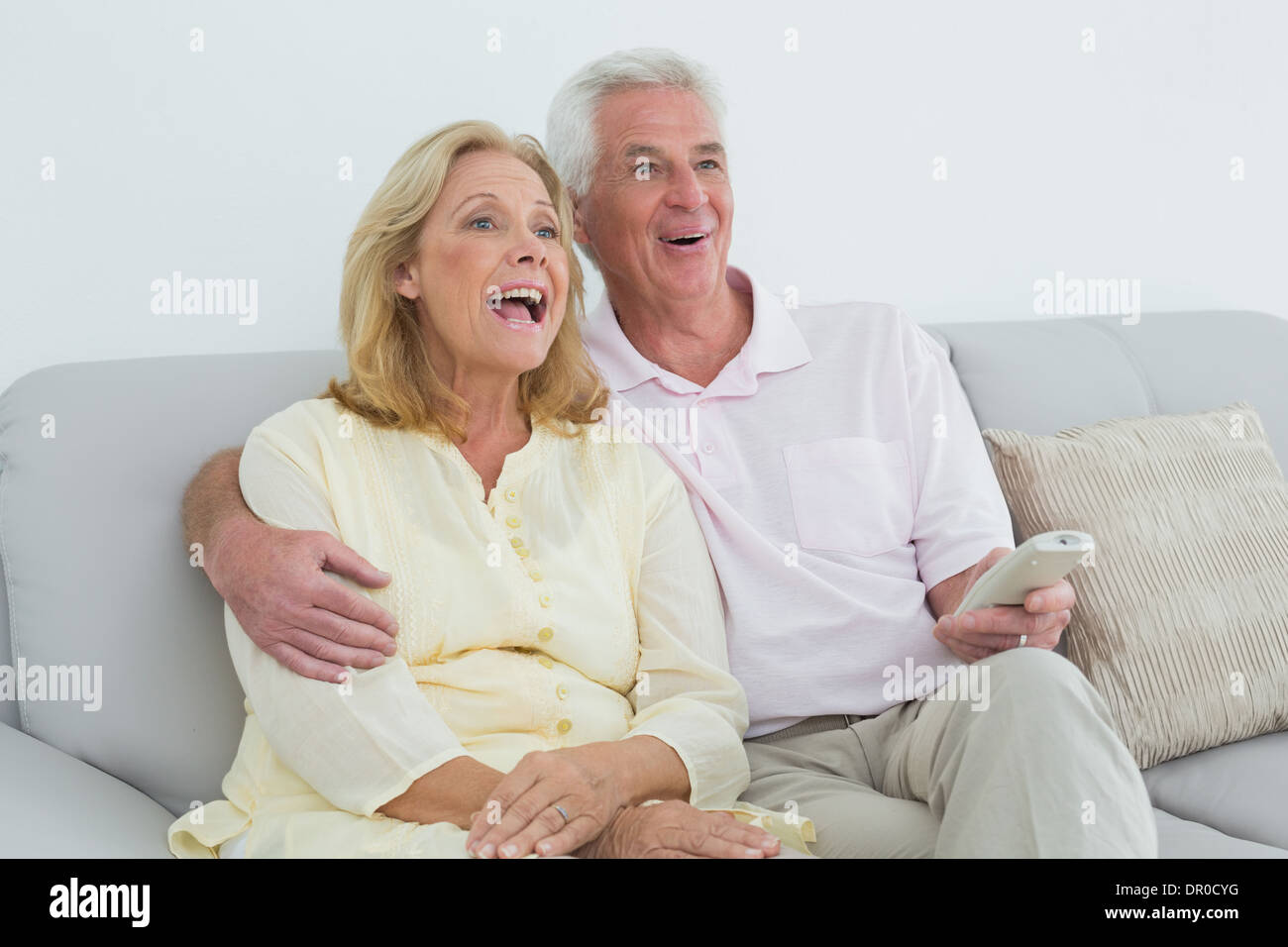 Cheerful senior couple avec télécommande à la maison Banque D'Images