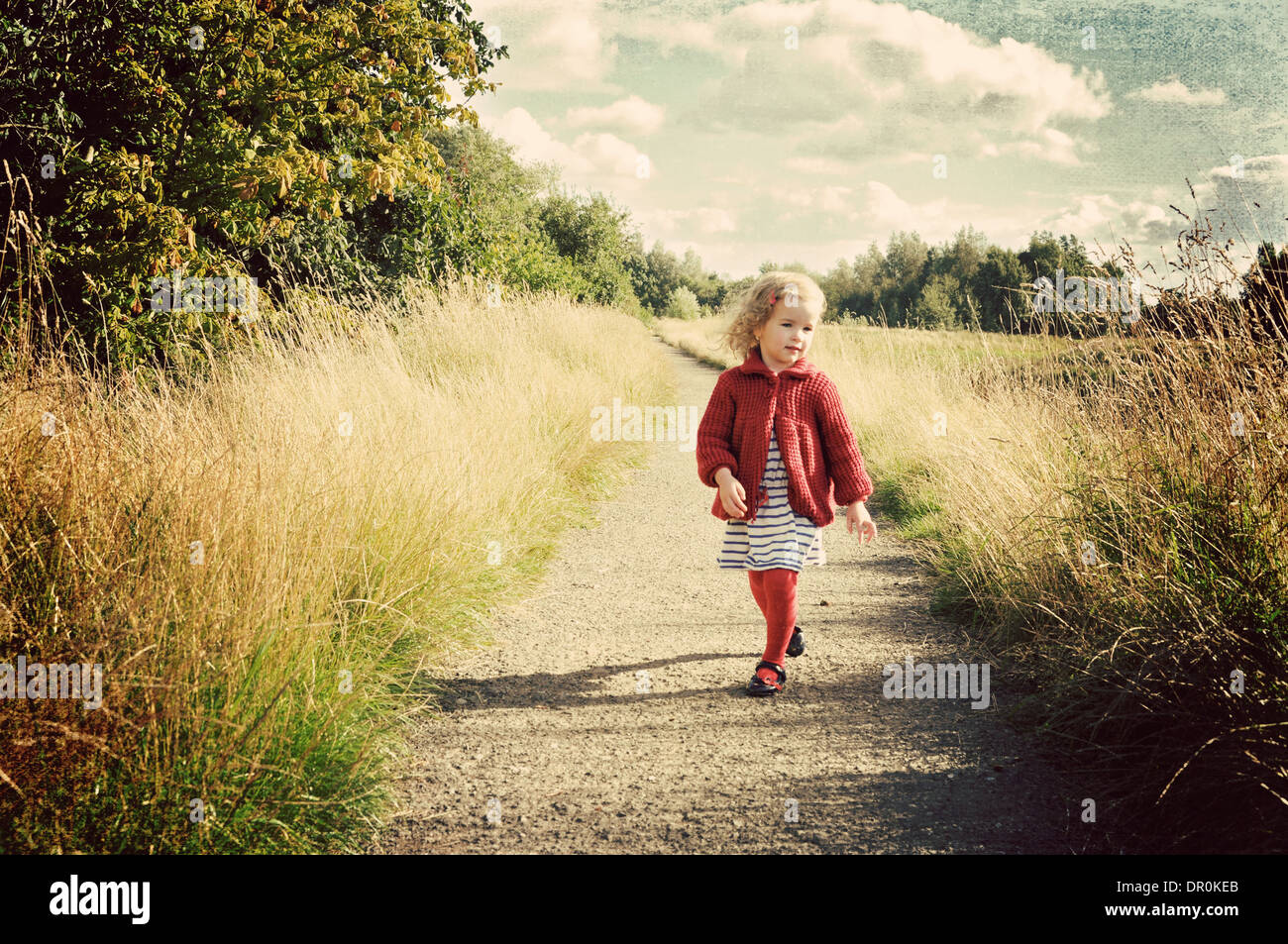 Petite fille qui marche le long du chemin de campagne. Banque D'Images
