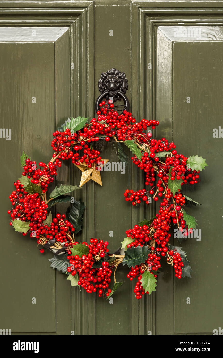 Porte avant de vert anglais traditionnel de style géorgien. Laurel de Noël de corail avec des baies rouges accrochés sur la porte. Banque D'Images