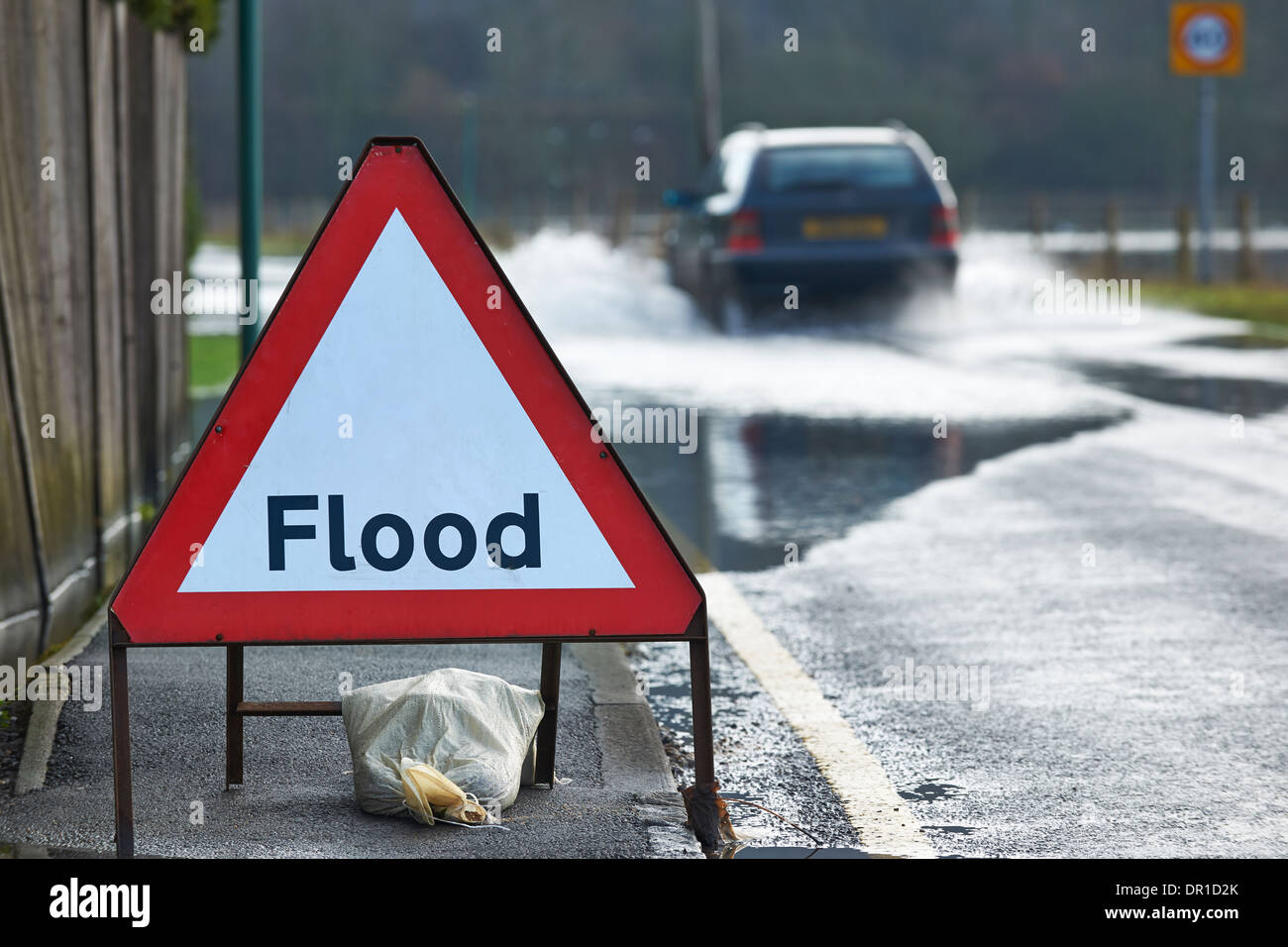 La conduite de l'automobiliste dans les eaux d'inondation avec panneau d'avertissement en premier plan Banque D'Images