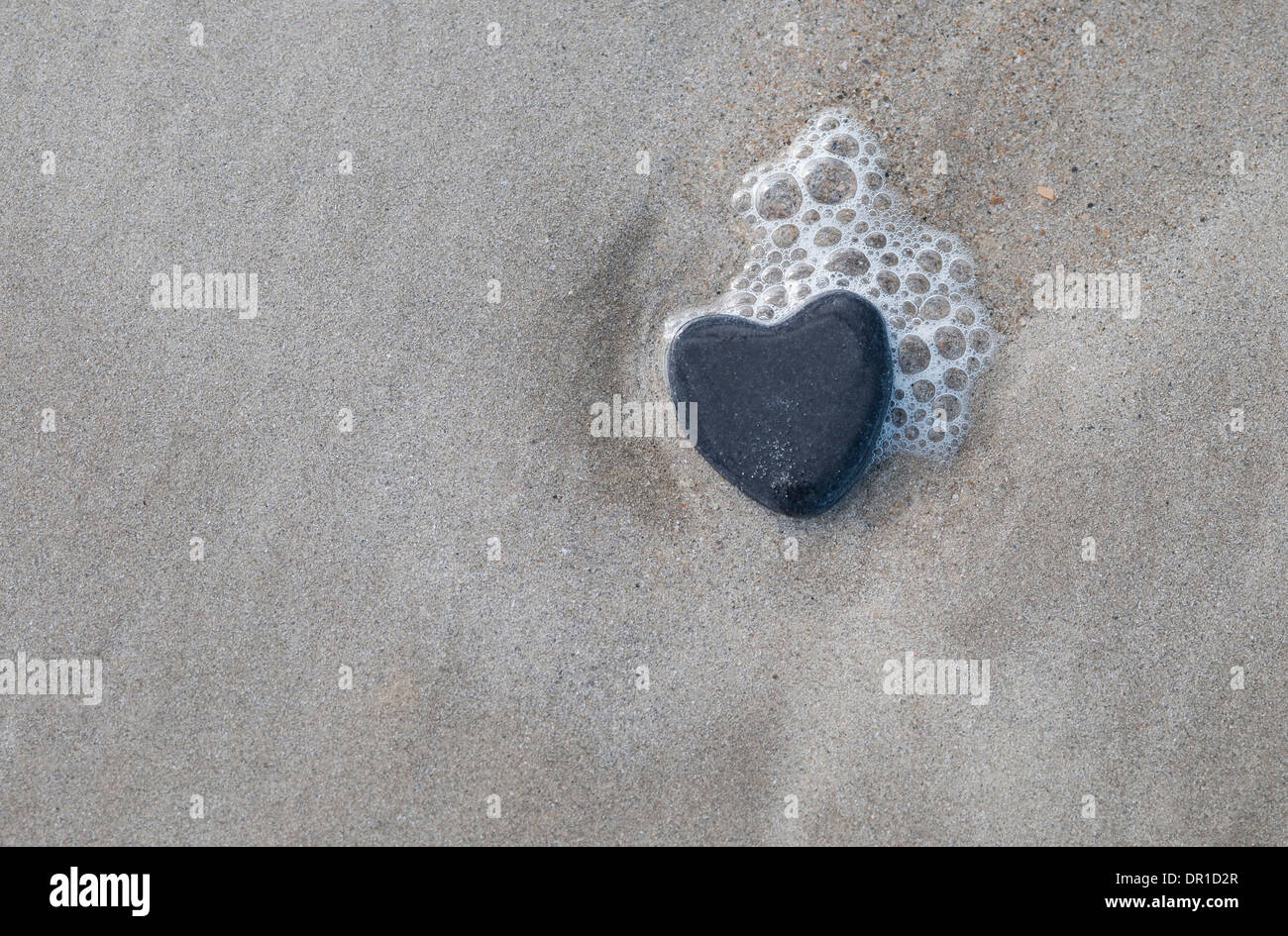 Pierre en forme de coeur sur le sable humide, Normandie, France Banque D'Images