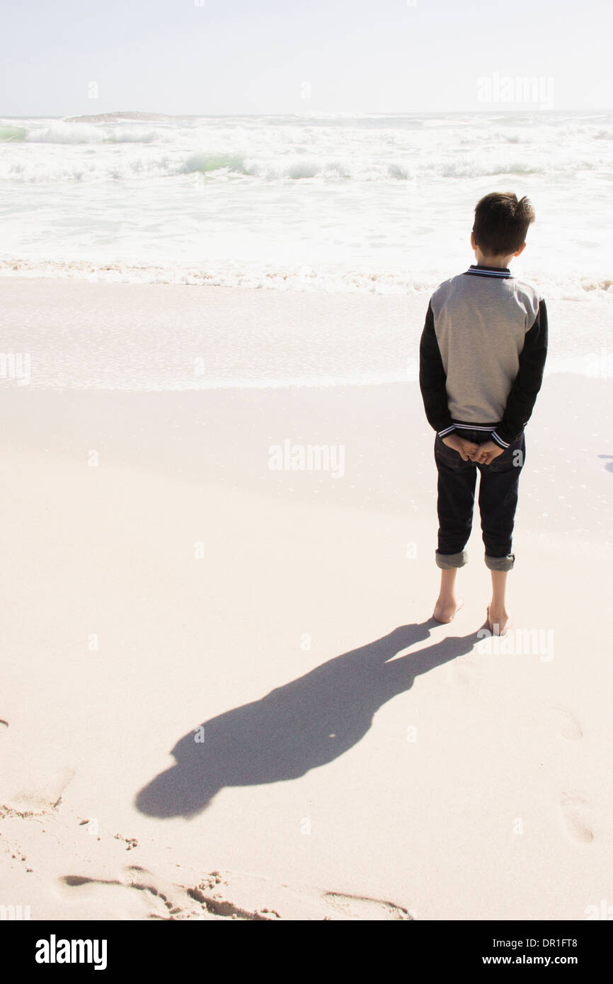 Boy standing on sunny beach Banque D'Images