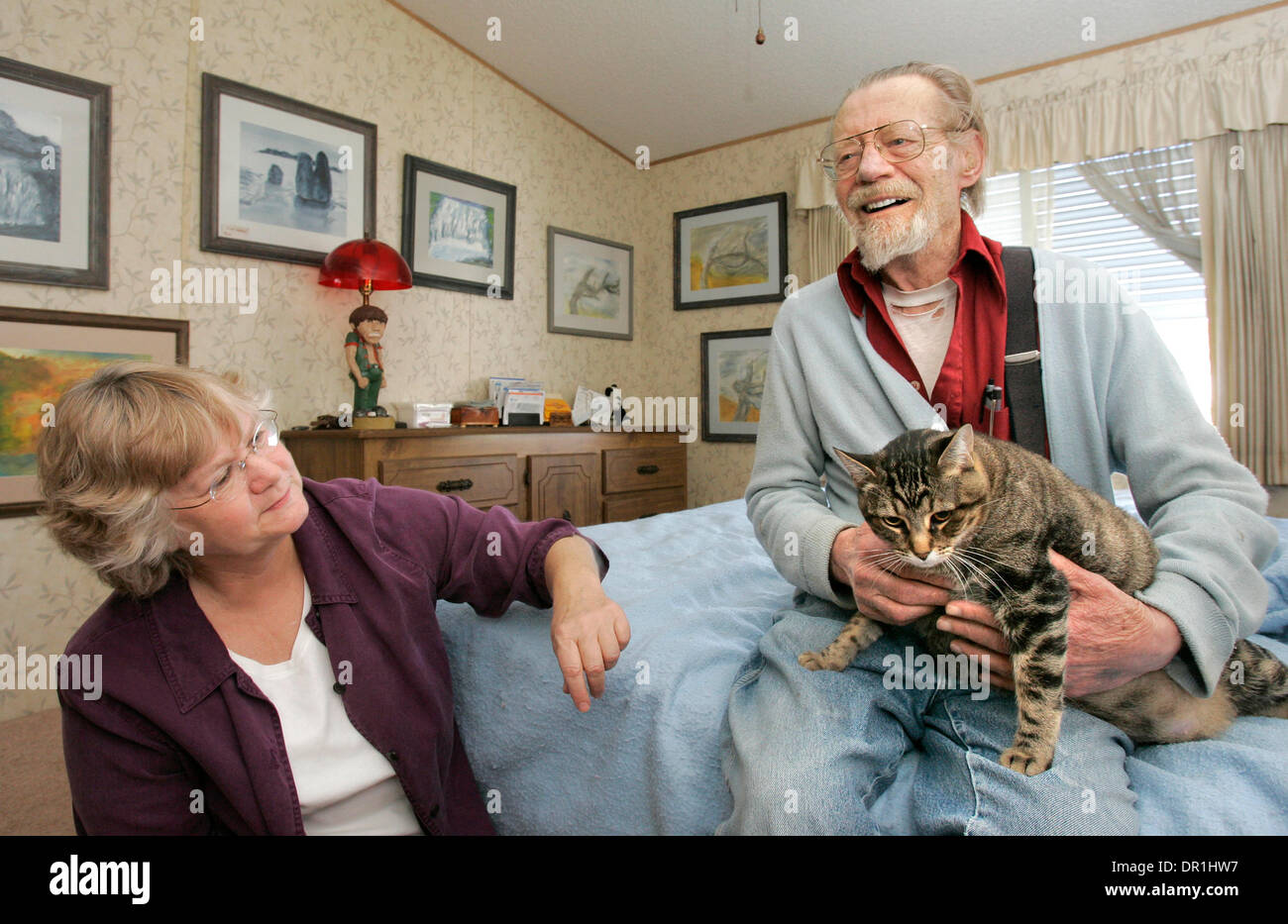 25 novembre 2008, Escondido, California, USA_79 ans JACK CALKINS est assis sur son lit comme il est titulaire d'Mama, un de ses deux chats. Il les nourrit avec des aliments livrés par Animeals, un programme de la Helen Woodward Animal Center. À gauche s'DIANNE WALTER, de repas sur roues, une organisation qui lui apporte quotidiennement de la nourriture_Credit : photo par Charlie Neuman, San Diego Union-Tribune/Zuma Press. copyr Banque D'Images