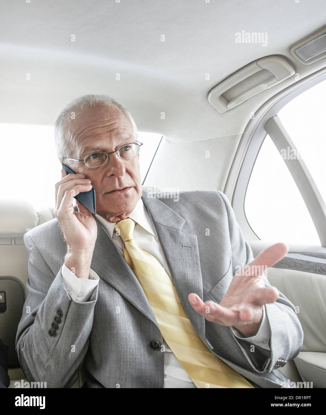 Caucasian businessman talking on cell phone in car Banque D'Images