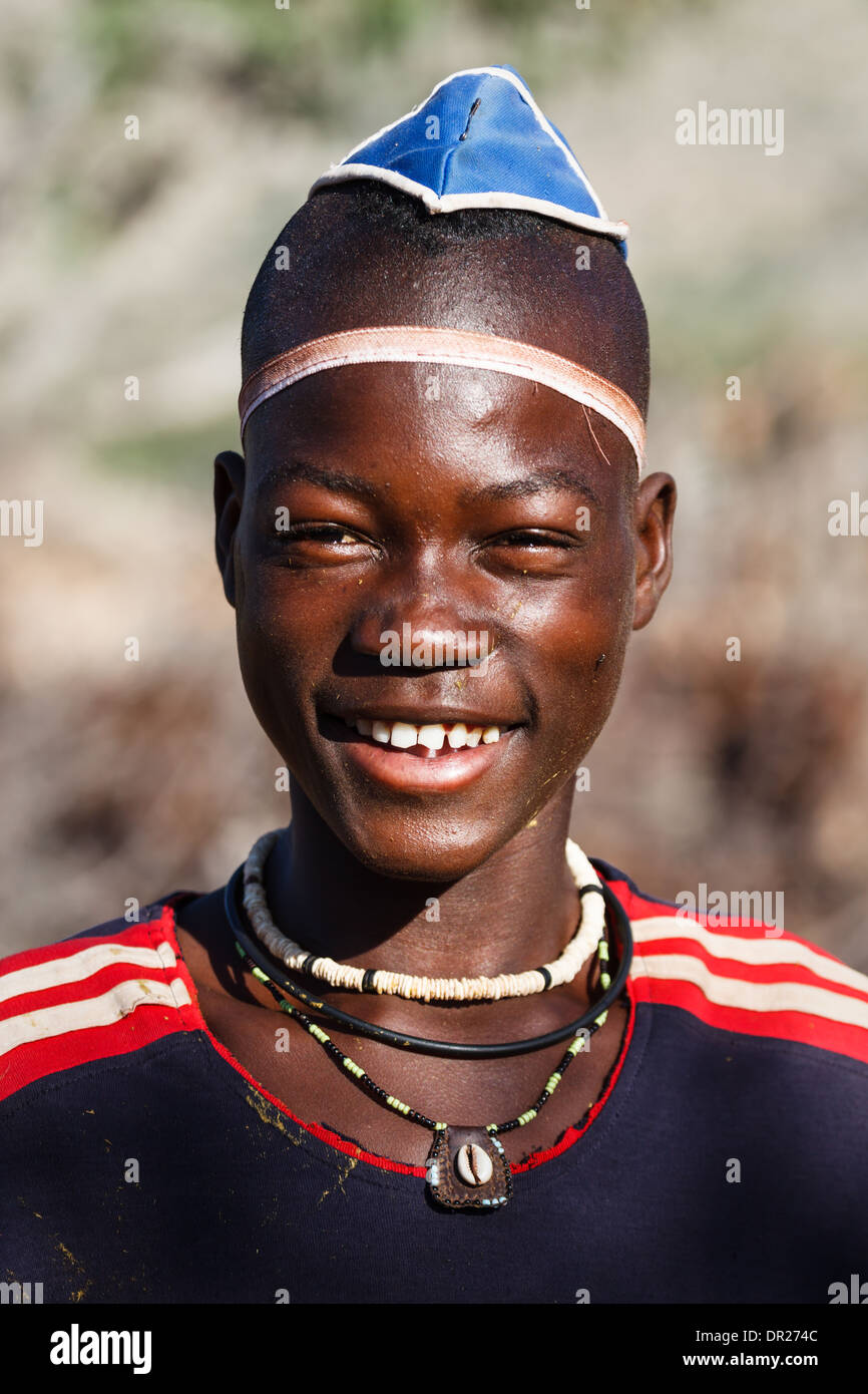 Teenage boy Smiling Himba, montre son couvre-chef et les perles dans le Damaraland, Namibie, Afrique Banque D'Images
