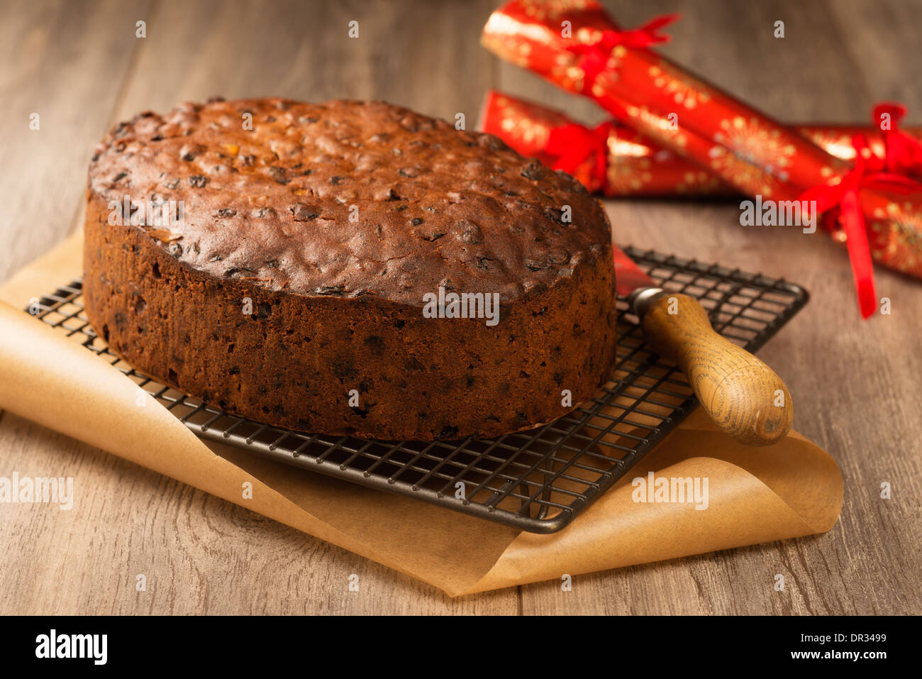 Gâteau aux fruits de Noël prêt à glace sur grille de refroidissement avec des craquelins à l'arrière-plan Banque D'Images