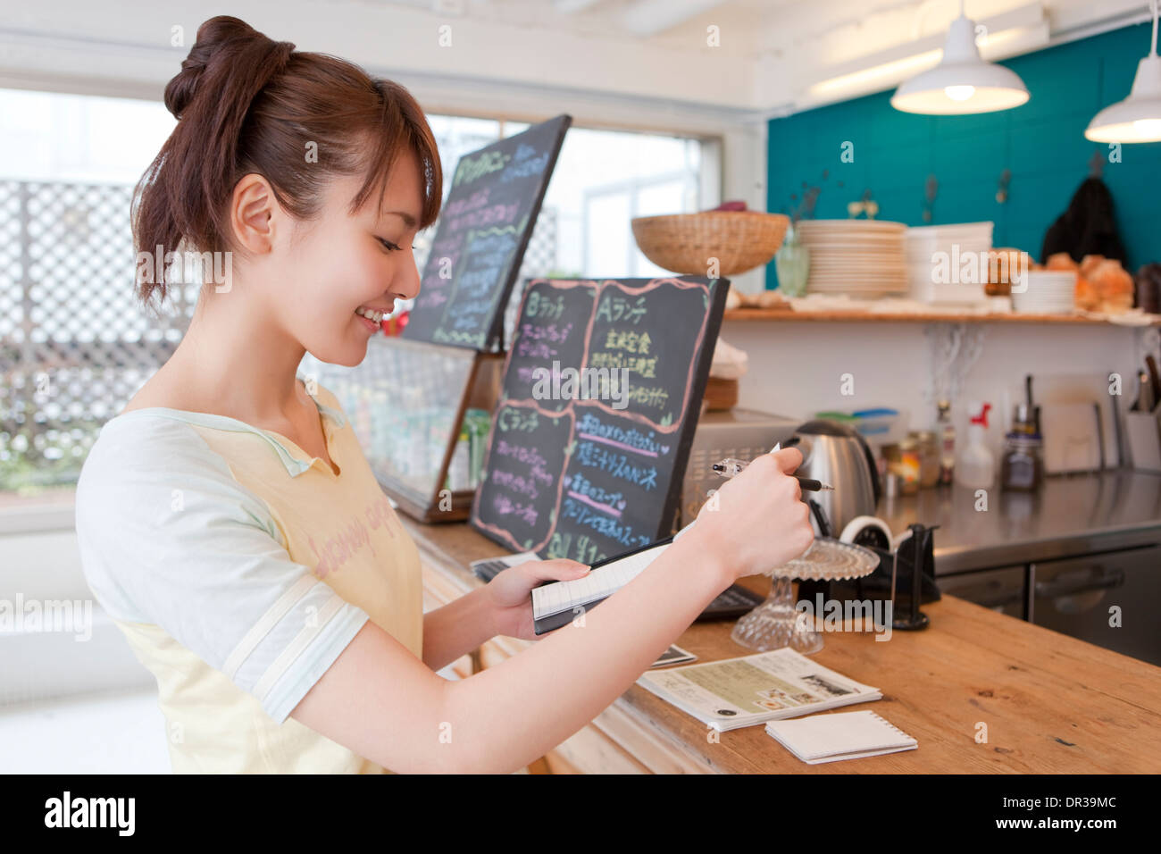 Jeune femme travaillant au café Banque D'Images