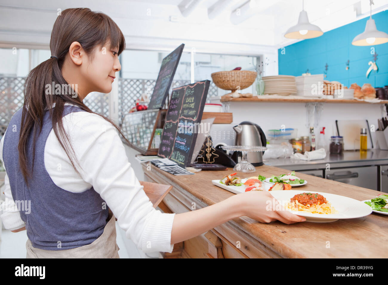 Jeune femme travaillant au café Banque D'Images