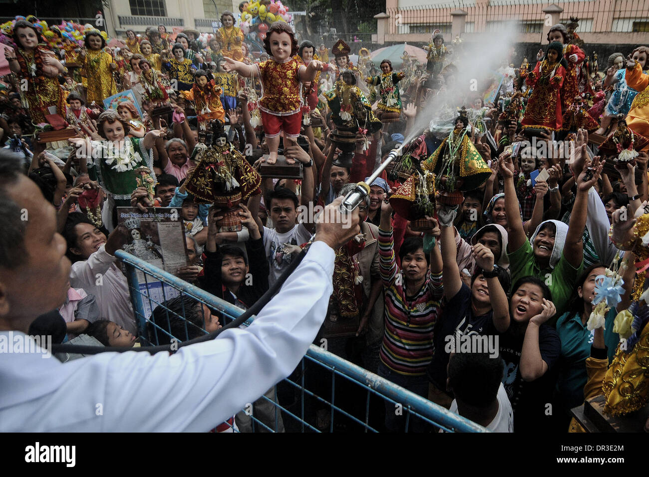 Manille, Philippines. 19 Jan, 2014. Les catholiques philippins élever leur Santo Nino statues qu'ils sont pulvérisés avec de l'eau bénite pendant la fête de Santo Nino dans une église dans le quartier pauvre de Tondo à Manille, Philippines, le 19 janvier 2014. Le festival est célébré chaque troisième dimanche de janvier, qui rend hommage à l'Enfant Jésus plus communément connue sous le nom de ''Santo Nino'' pour les catholiques philippins.Photo : Ezra Acayan/NurPhoto Acayan Crédit : Ezra/NurPhoto ZUMAPRESS.com/Alamy/Live News Banque D'Images