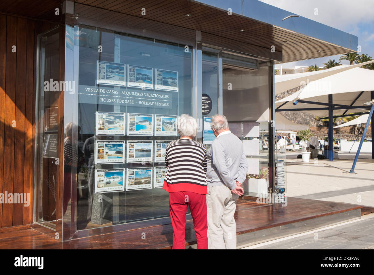 Couple de retraités personnes âgées à la retraite à la recherche de propriétés à vendre et à louer dans une fenêtre de l'agent immobilier à Puerto Calero, Lanzarote, Îles Canaries Banque D'Images
