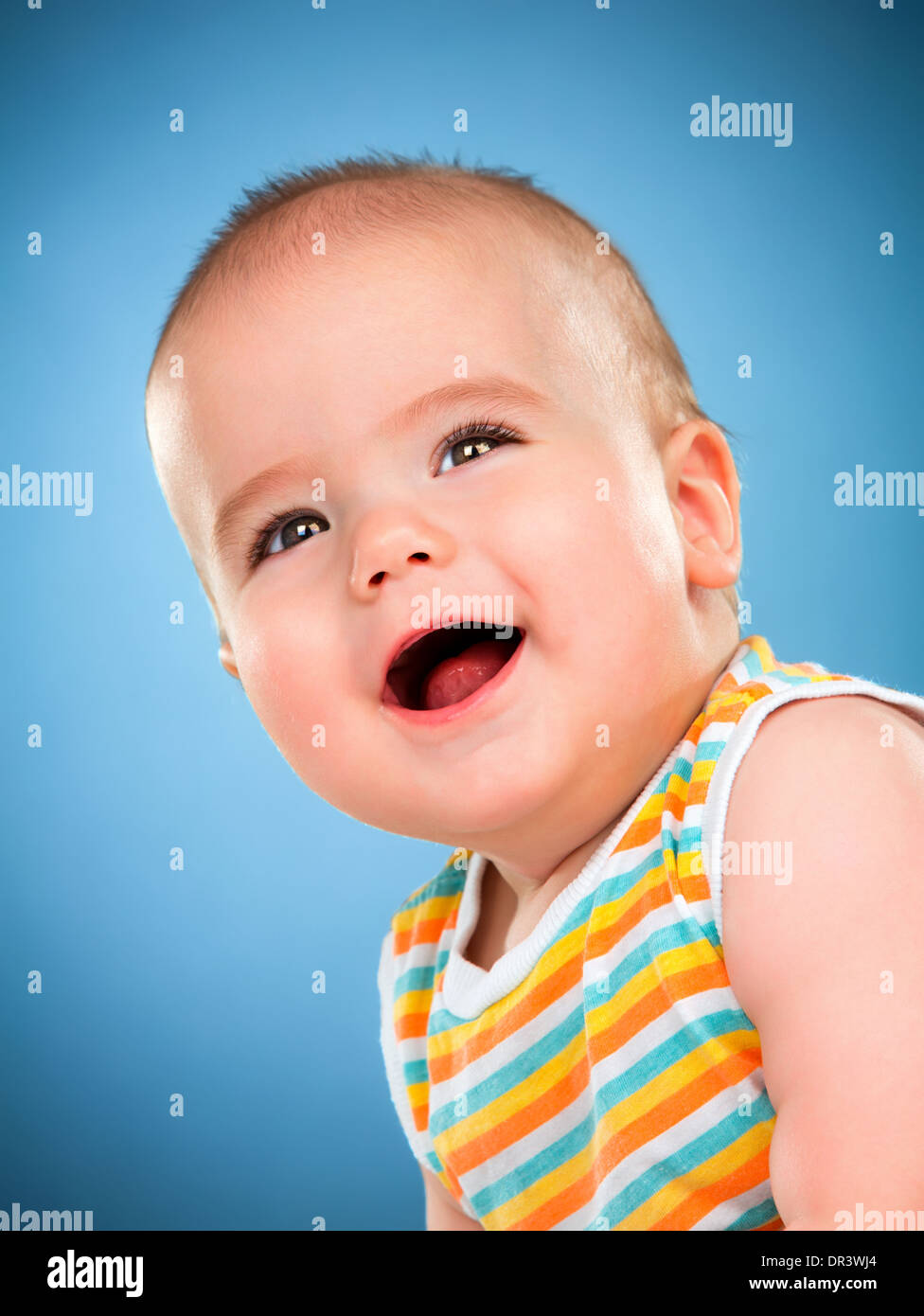 Petit bébé heureux isolé sur un fond bleu. Banque D'Images