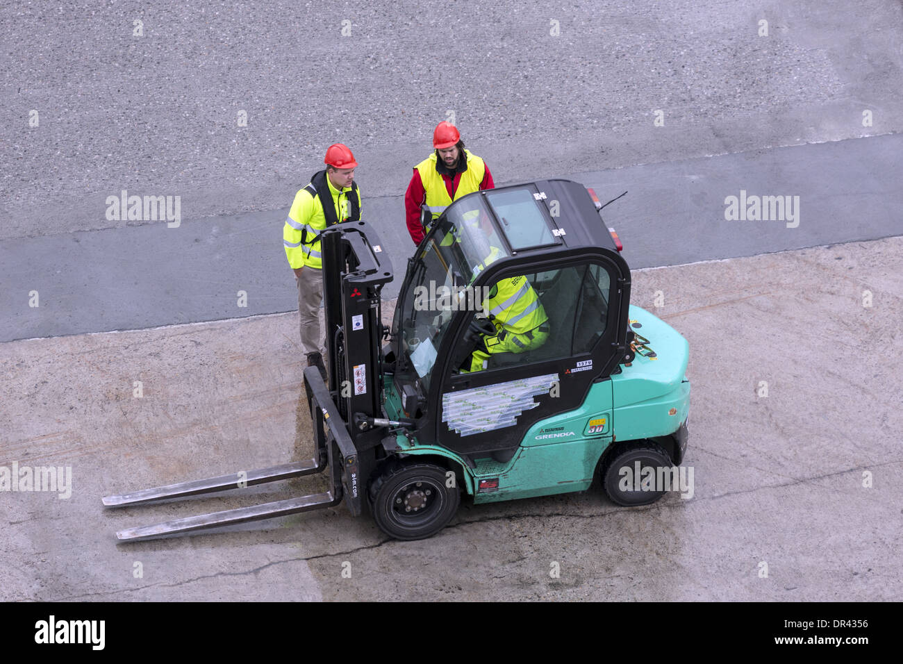 Deux hommes parler au conducteur d'un petit chariot élévateur Banque D'Images